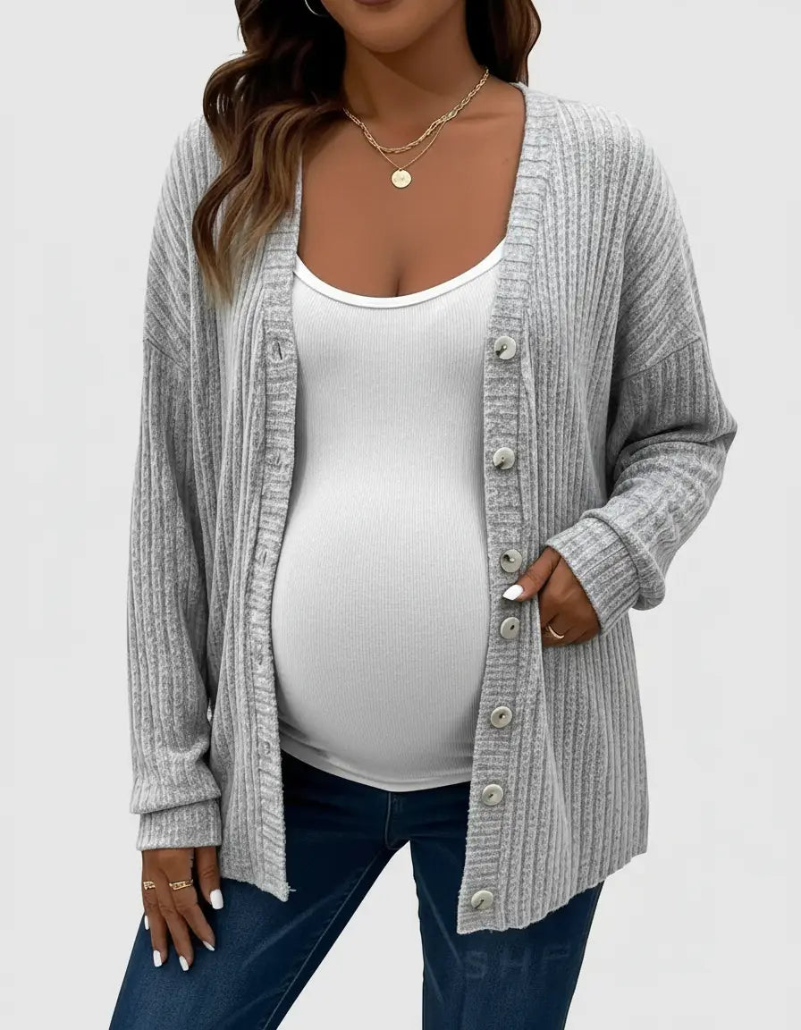 Maternity model wearing a light gray ribbed button-front drop shoulder cardigan over a white tank top and jeans.