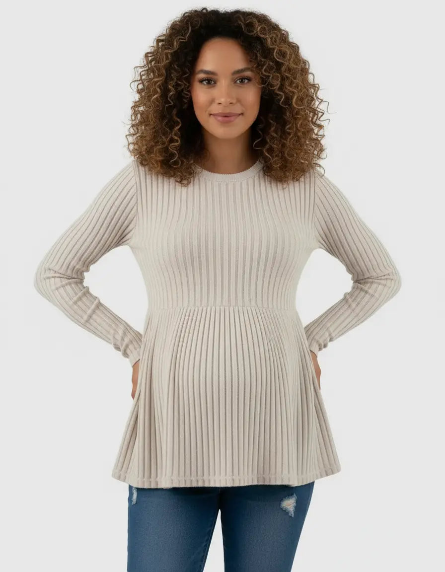 Smiling pregnant woman in a beige ribbed knit maternity top with a ruffle hem.