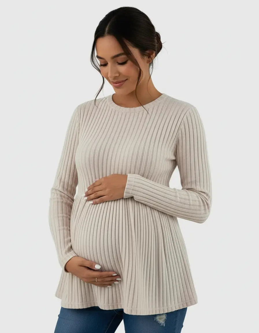 Pregnant woman in a beige ribbed knit maternity top with long sleeves and a ruffle hem.