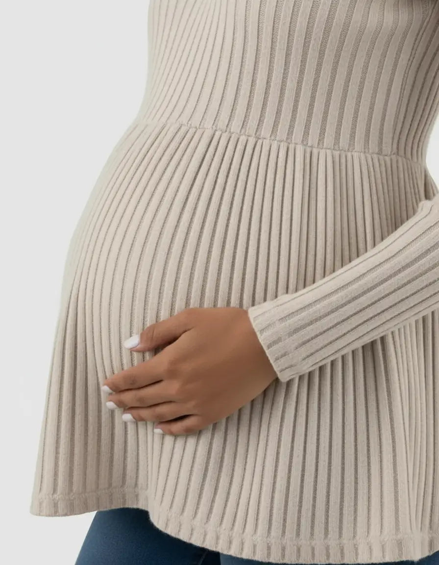 Beige ribbed knit maternity top with ruffle hem, worn by a pregnant woman.