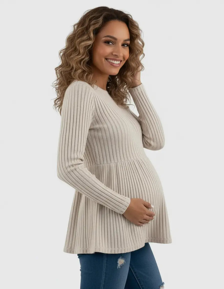 Smiling pregnant woman in a beige ribbed knit maternity top with a ruffle hem.