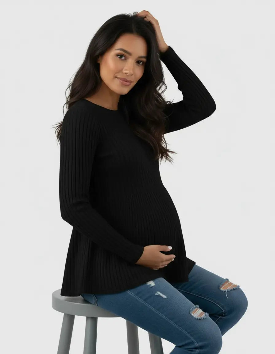 Pregnant woman in a black ribbed knit ruffle hem maternity top and distressed jeans.