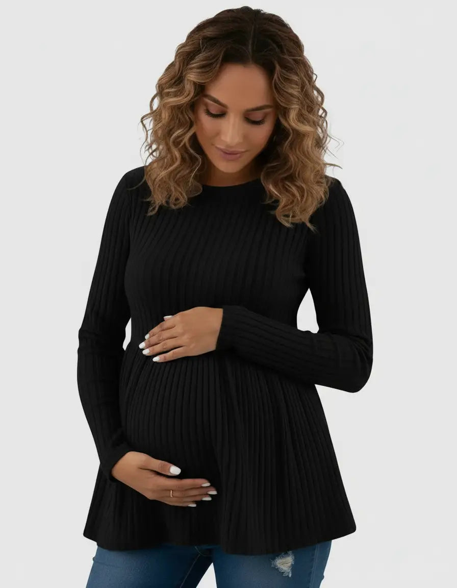 Maternity model in a black ribbed knit long-sleeve top with a ruffle hem, cradling her baby bump.