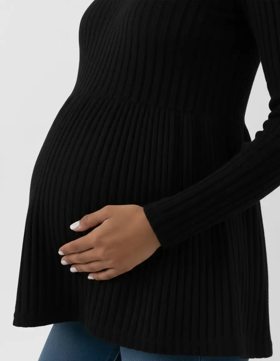 Black ribbed knit maternity top with long sleeves and ruffle hem, worn by a pregnant woman.