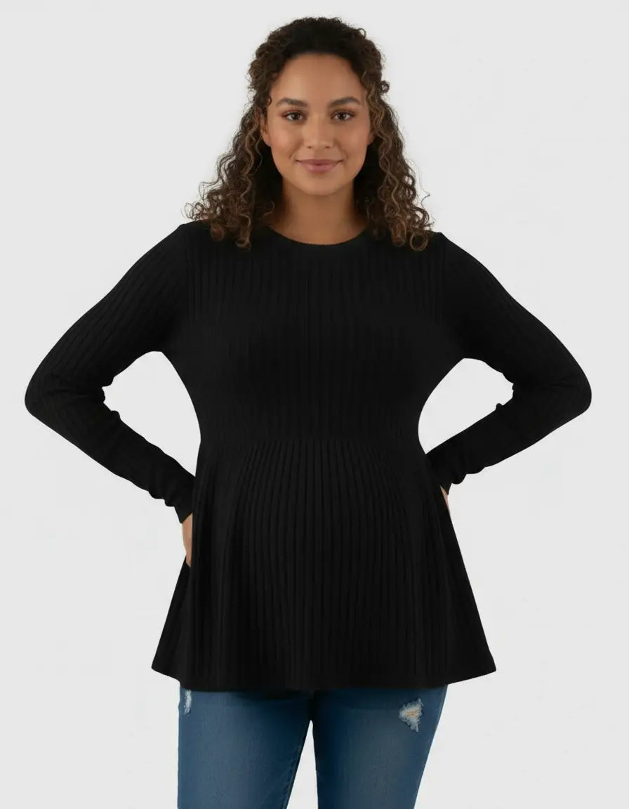 Smiling pregnant woman in a black ribbed knit maternity top with a ruffle hem, paired with distressed jeans.
