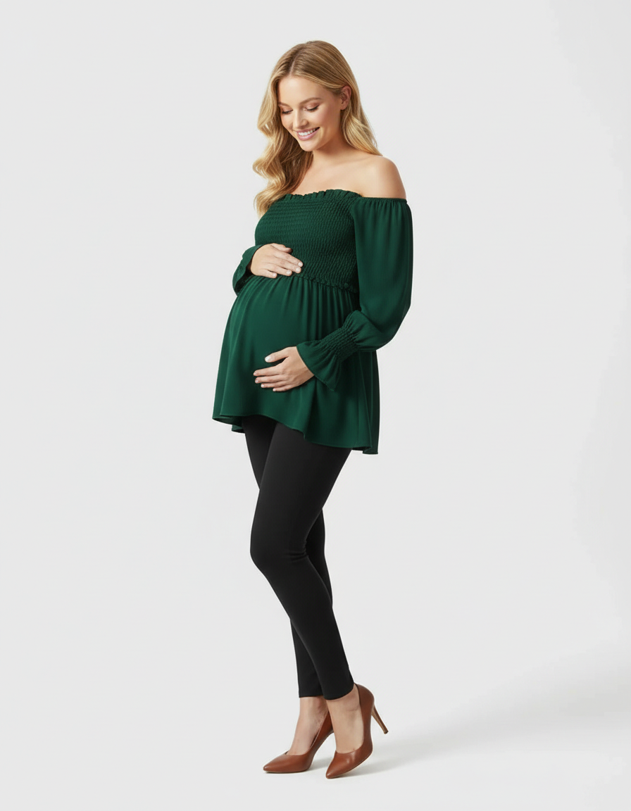 Smiling pregnant woman in a dark green ruched off-shoulder maternity top and black leggings.
