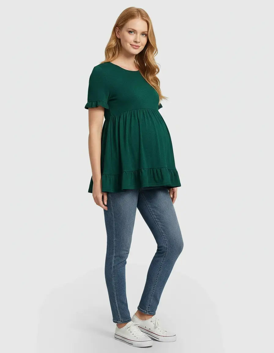 Woman in a green ruffled-sleeve flowy maternity top and blue jeans.