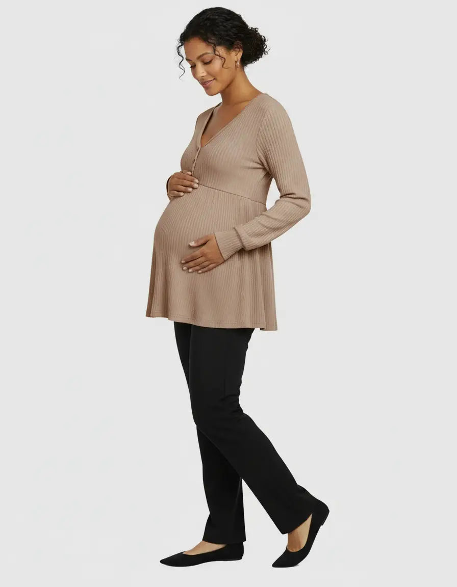Pregnant woman in a beige ribbed V-neck maternity top with ruffled details and black pants.