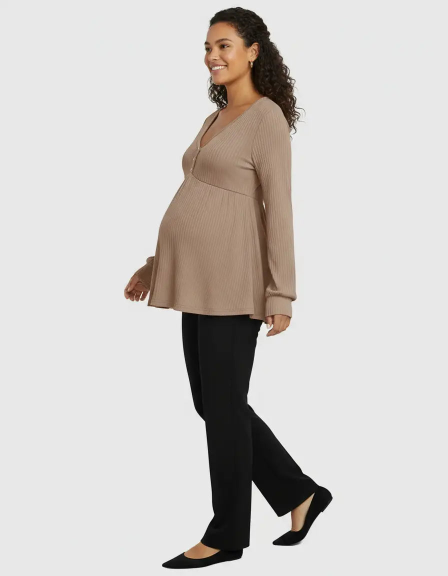 Pregnant woman in a beige ribbed, ruffled V-neck maternity top and black pants.