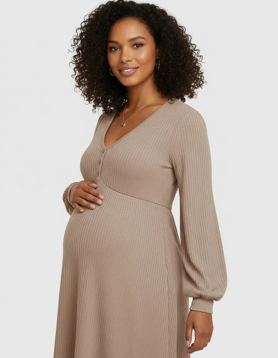 Smiling pregnant woman in a beige ribbed V-neck maternity top with long balloon sleeves and button details.