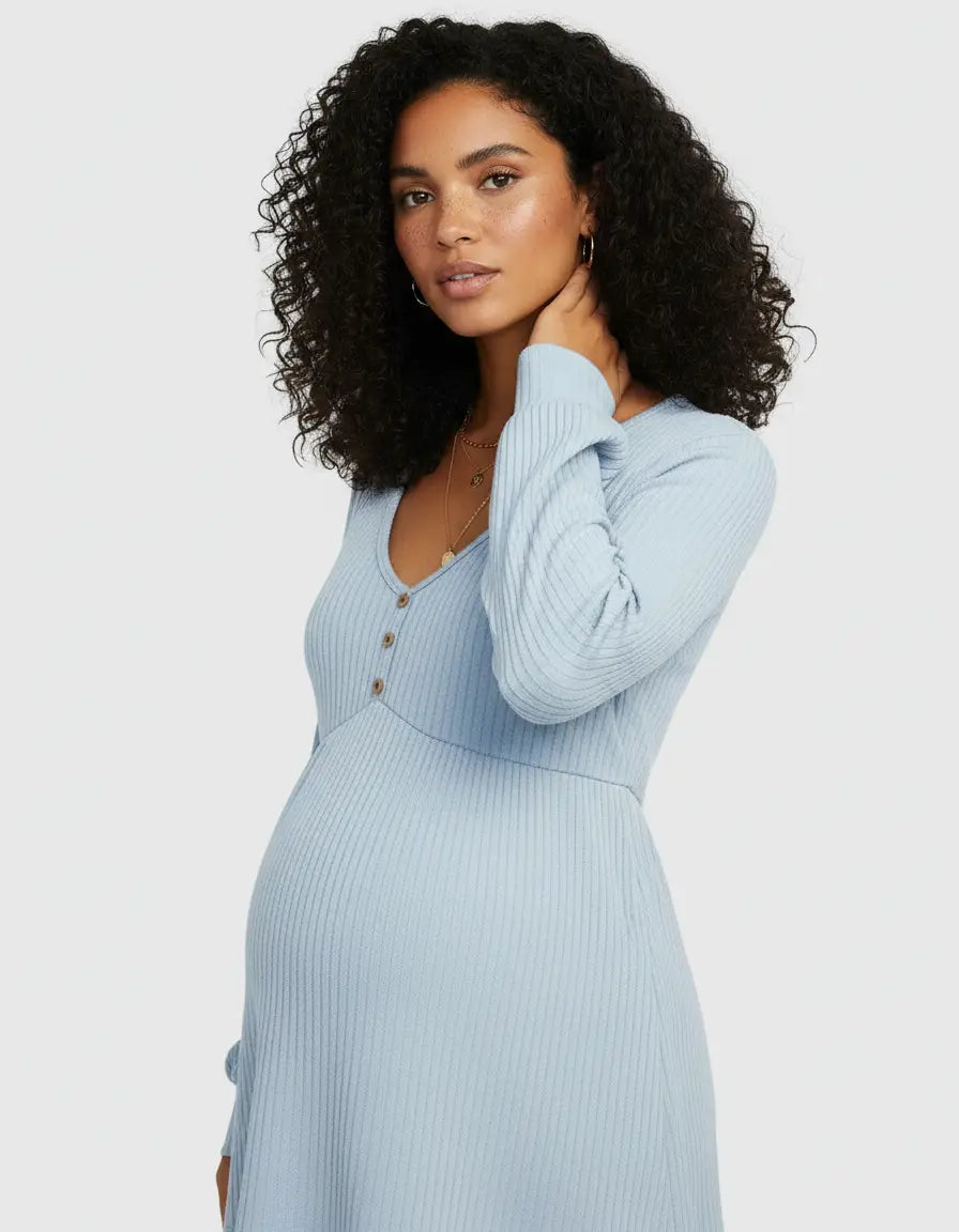 Pregnant woman in a light blue ribbed maternity top with a ruffled V-neck and button details.