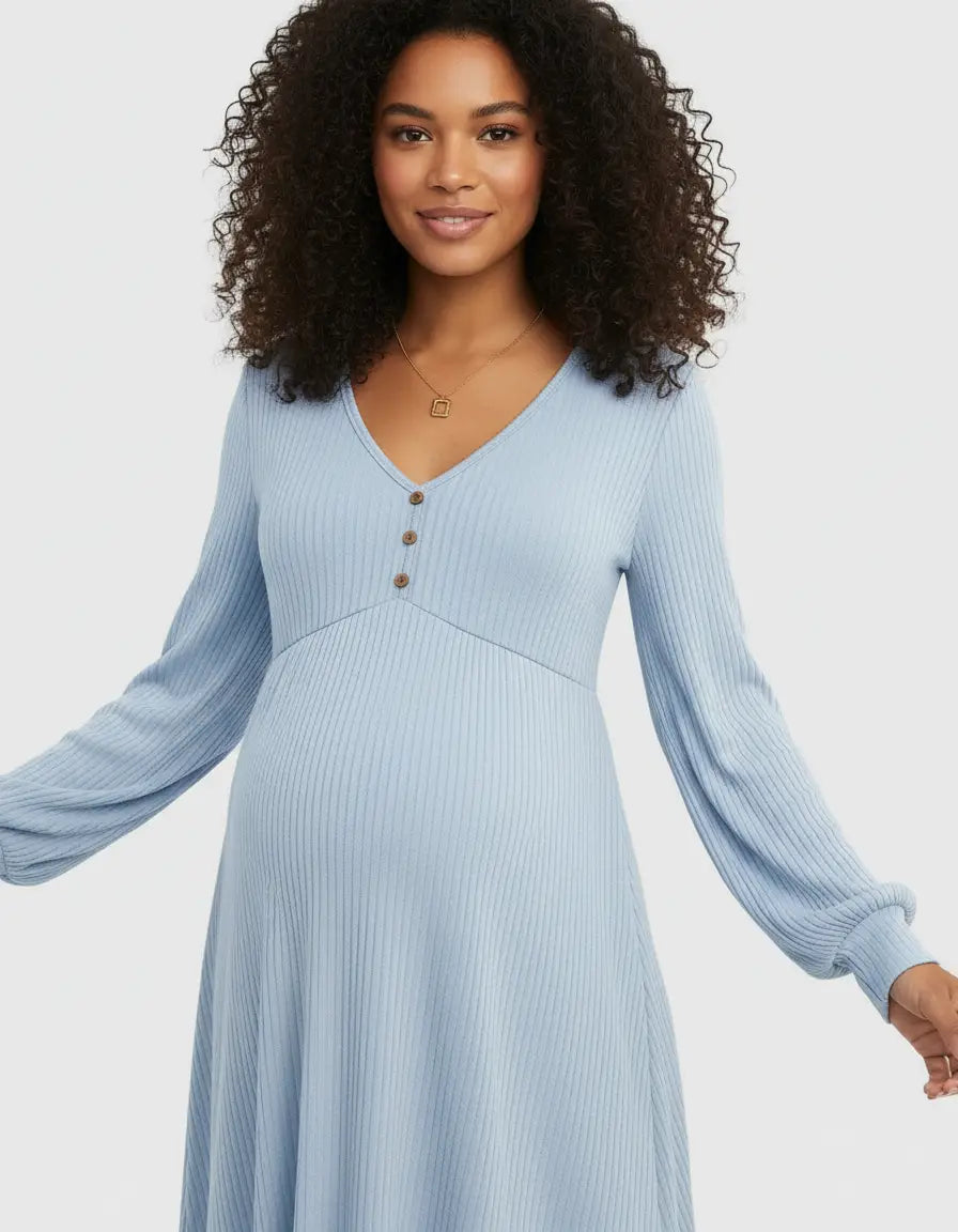 Smiling pregnant woman in a light blue ribbed maternity top with a ruffled V-neck and button details.