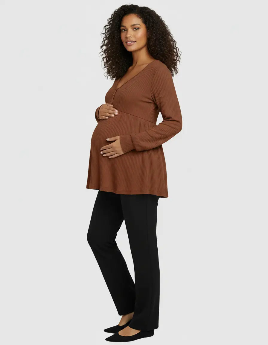 Pregnant woman in a brown ribbed V-neck maternity top with long sleeves and black pants.