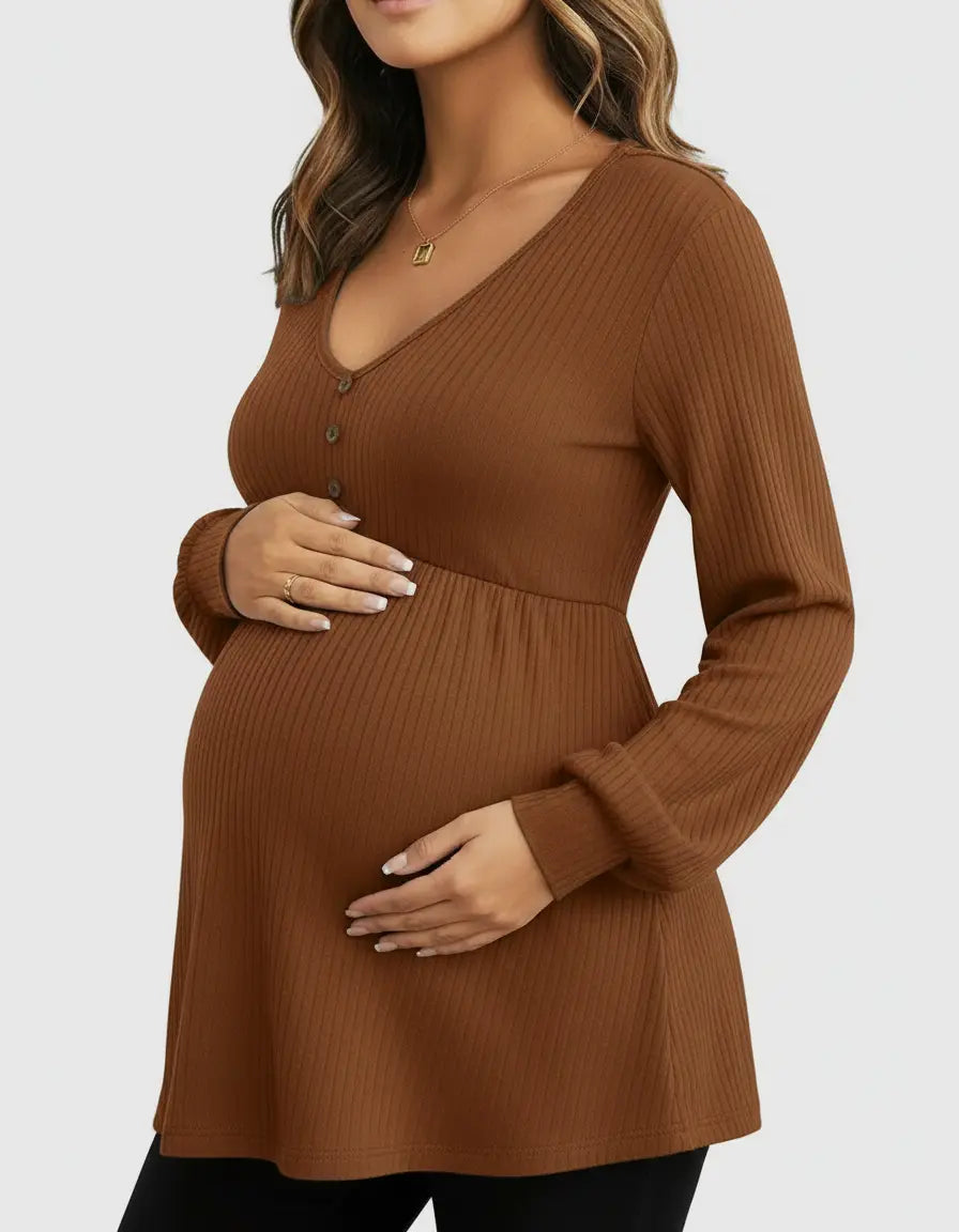 Pregnant woman in a brown ribbed V-neck maternity top with long sleeves, holding her baby bump.