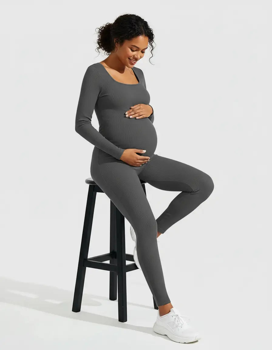 Smiling pregnant woman in a charcoal gray seamless ribbed maternity bodysuit with a square neckline, ankle-length.