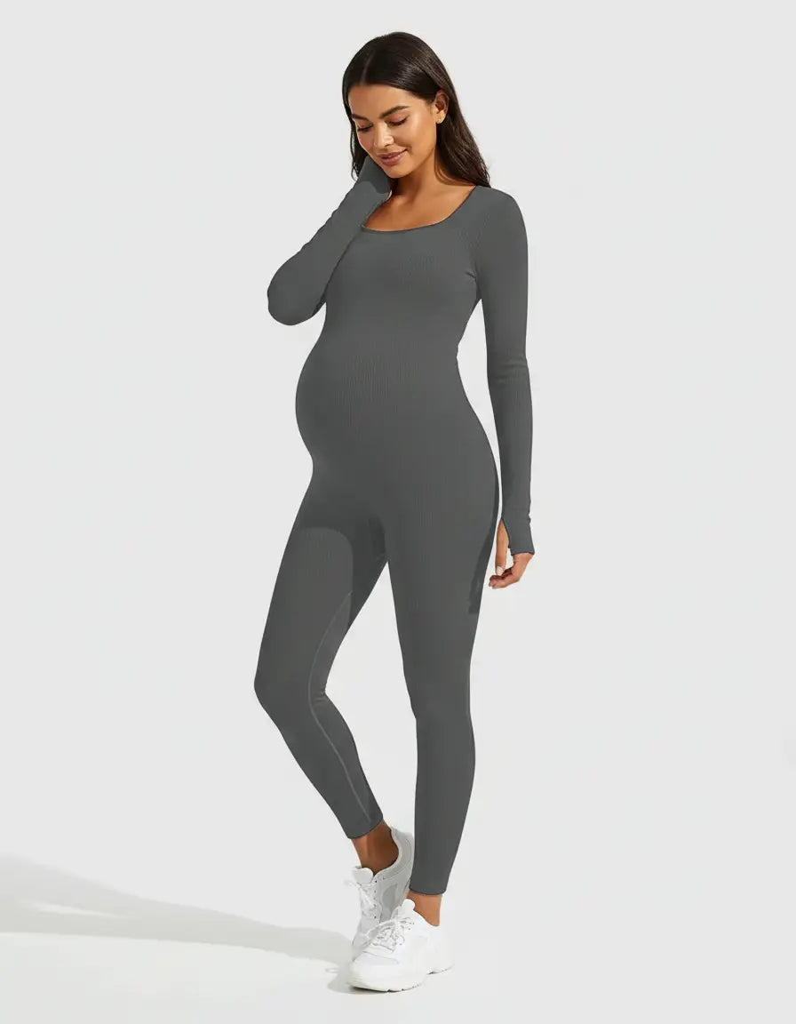 Smiling pregnant woman in a dark gray ribbed seamless ankle-length maternity bodysuit with long sleeves.