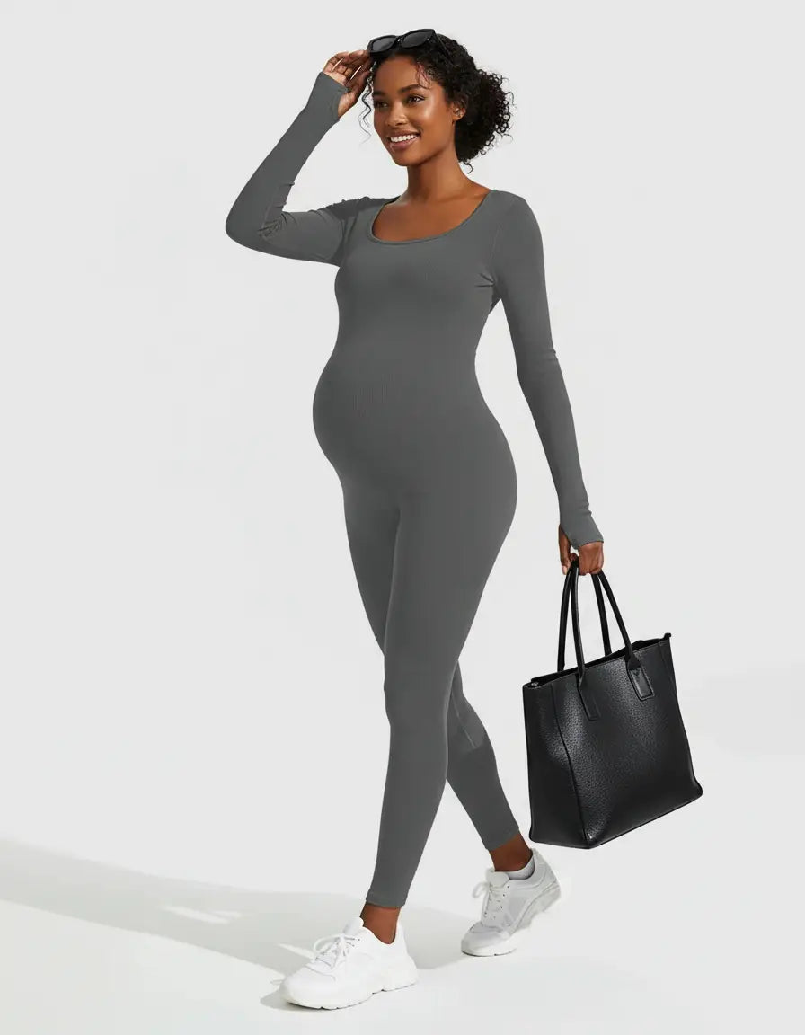 Smiling pregnant woman in a gray seamless ankle-length maternity bodysuit, white sneakers, and a black tote bag.