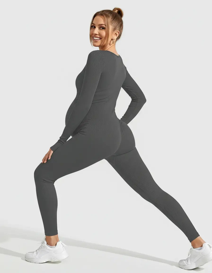 Smiling pregnant woman in a dark grey ribbed seamless ankle-length maternity bodysuit.