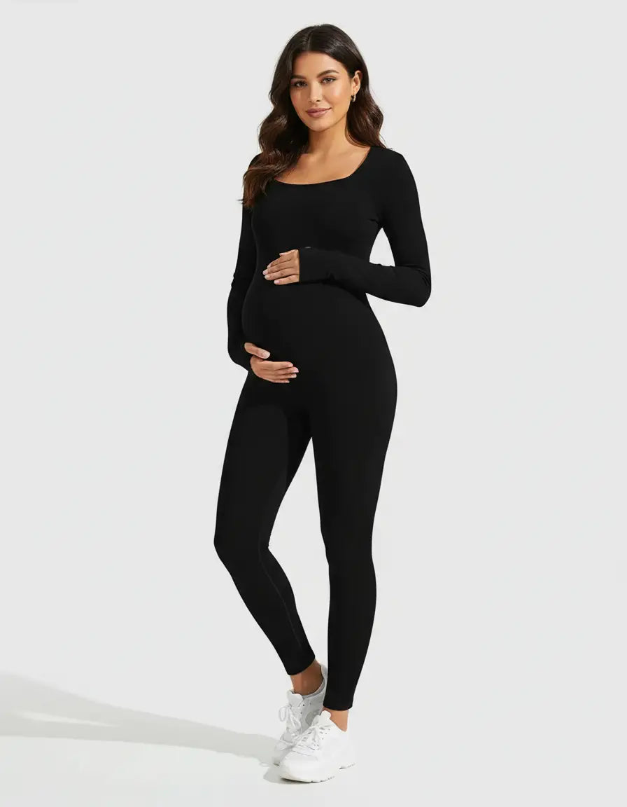Pregnant woman in a black seamless ankle-length maternity bodysuit with a scoop neck, holding her belly.