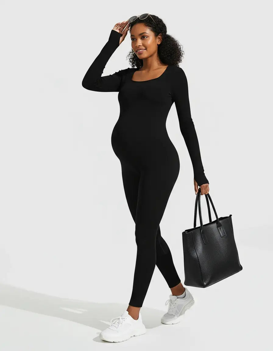 Smiling pregnant woman in a black seamless ankle-length maternity bodysuit with a square neckline, holding a tote bag.