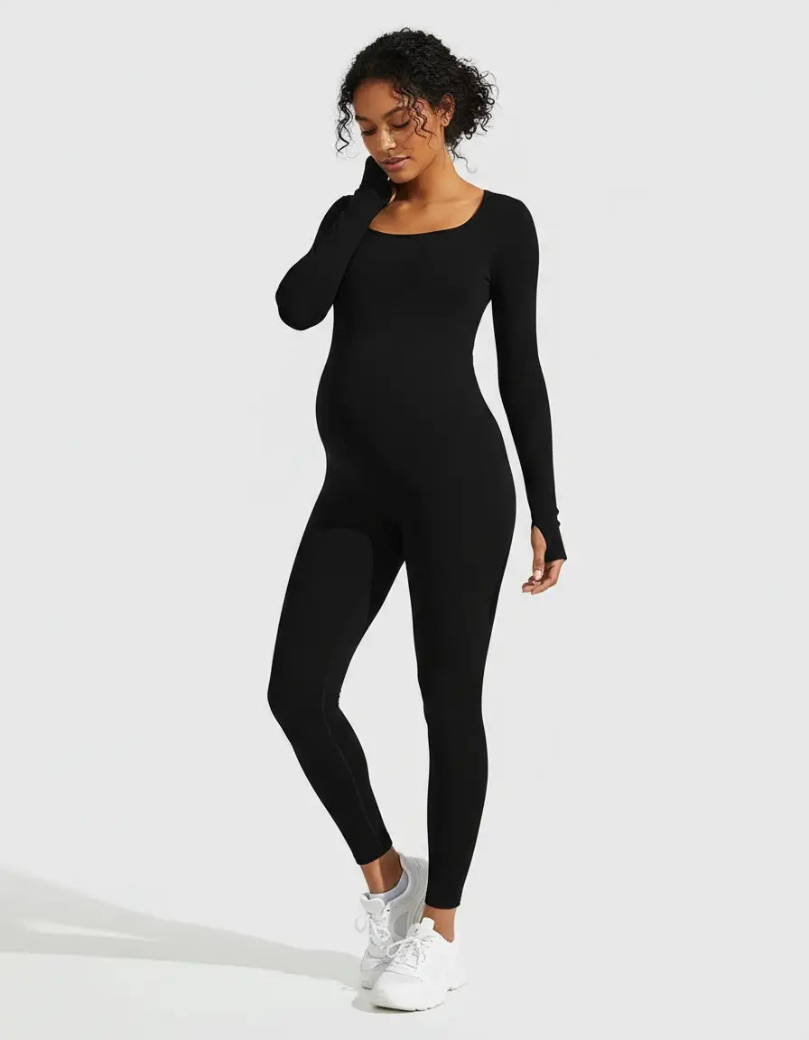 Pregnant woman wearing a black seamless ankle-length maternity bodysuit with long sleeves and thumbholes.
