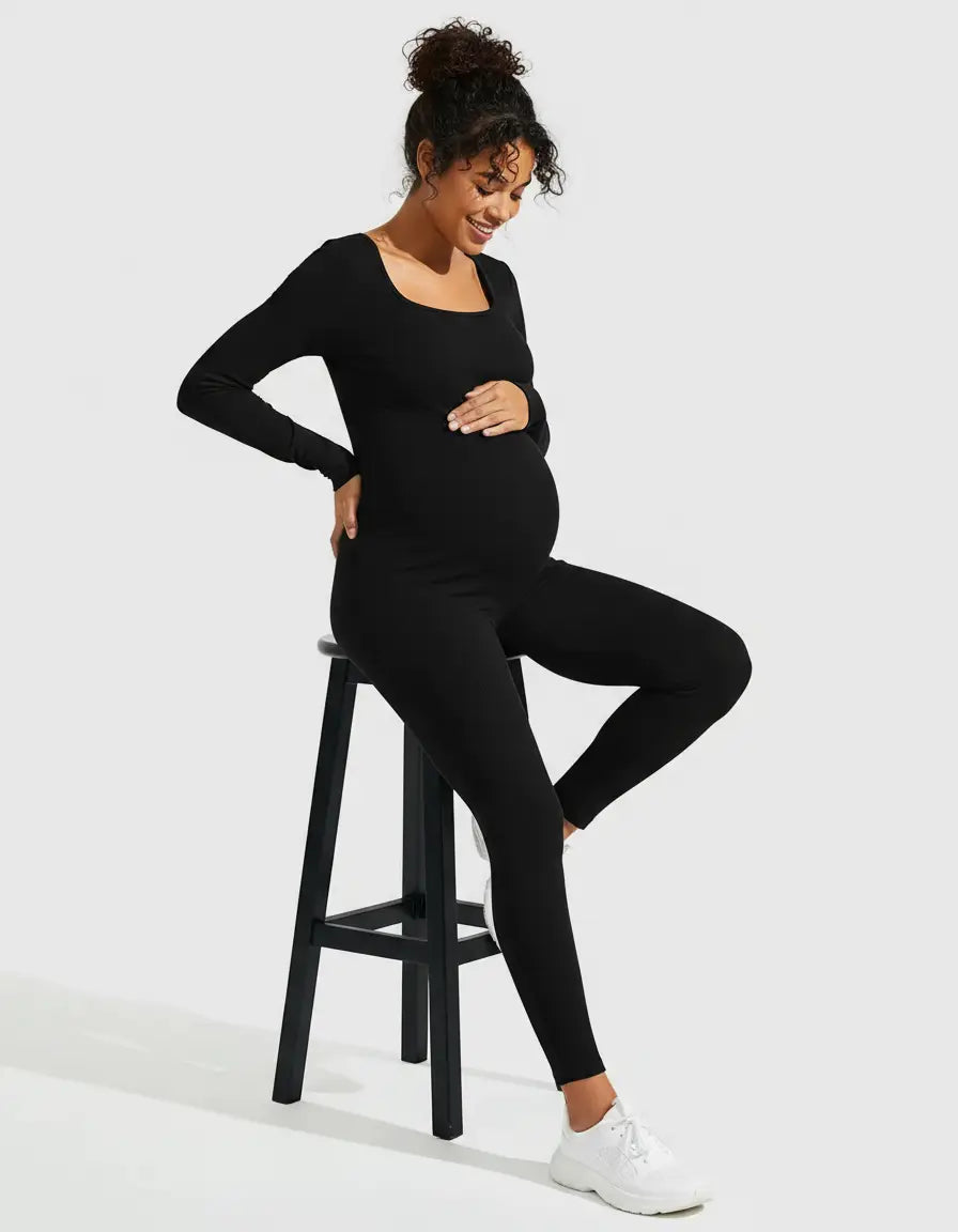 Smiling pregnant woman in a black seamless ribbed maternity bodysuit with a square neck and long sleeves.