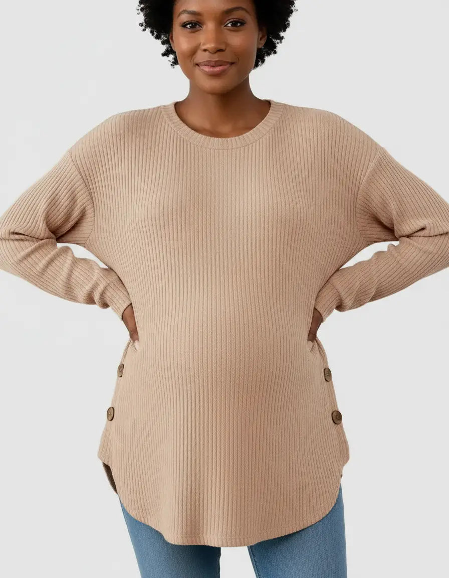 Smiling woman models a beige soft-knit relaxed-fit maternity sweatshirt with side buttons and a curved hem.
