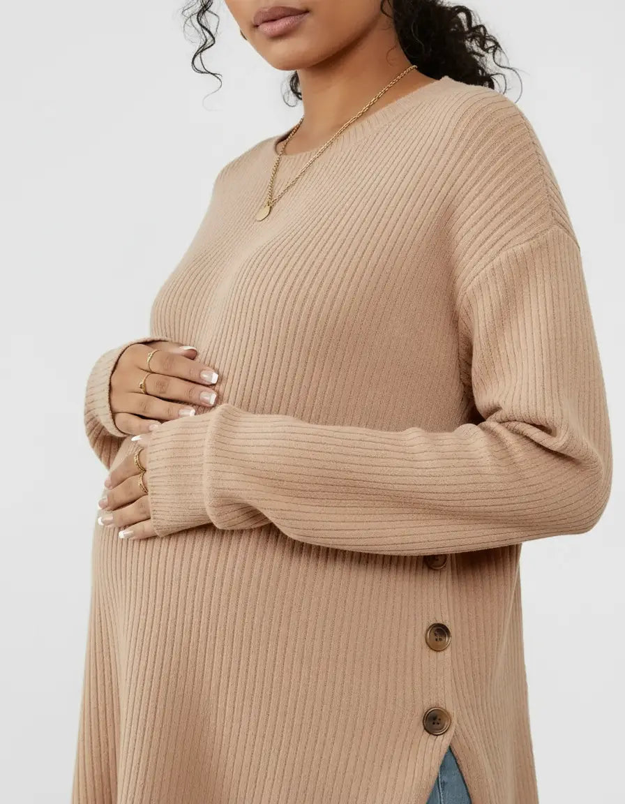 Pregnant woman wearing a soft-knit, relaxed-fit, beige maternity sweatshirt with side buttons.