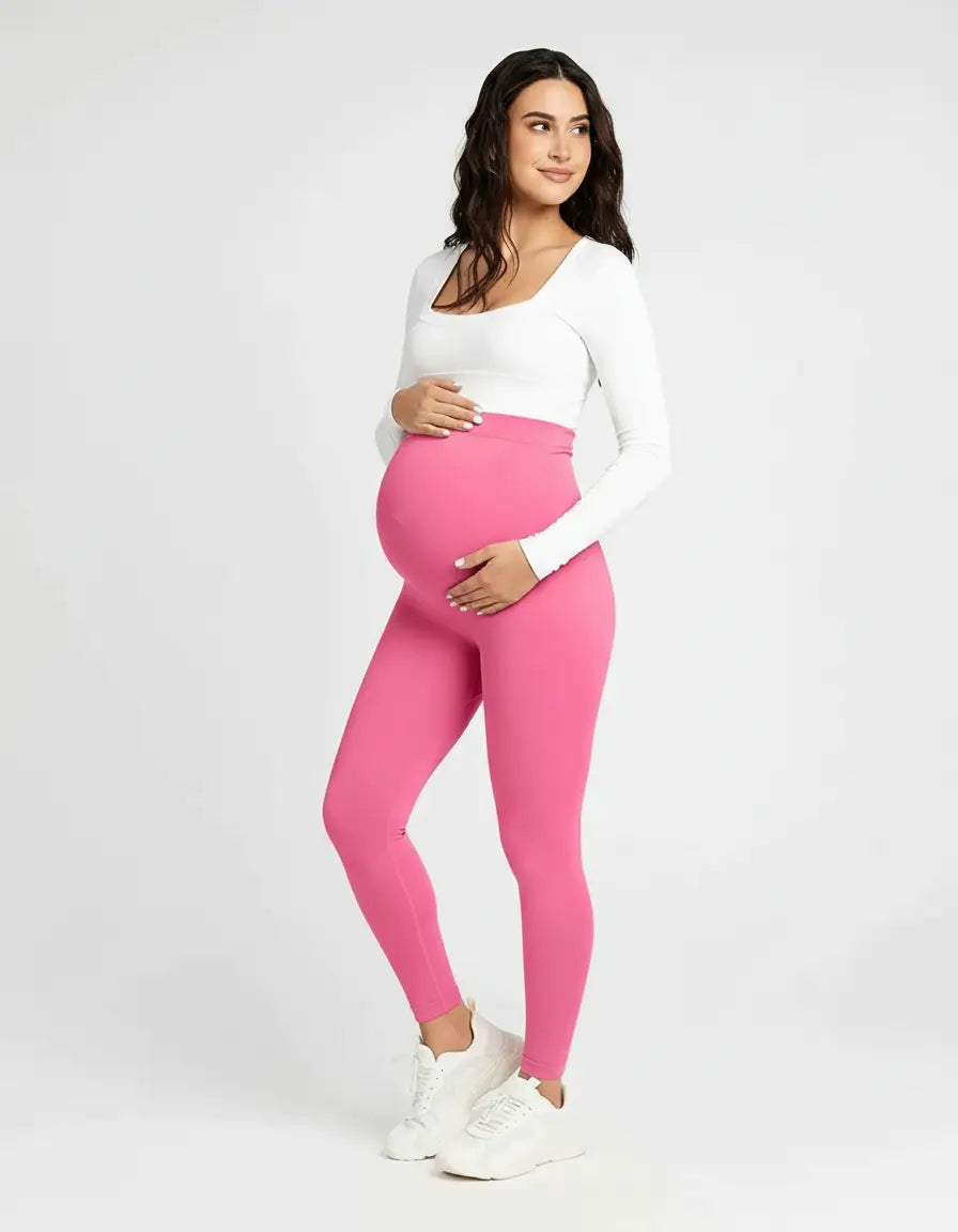 Smiling pregnant woman in full-length, soft-stretch hot pink maternity leggings with a high, supportive waist.