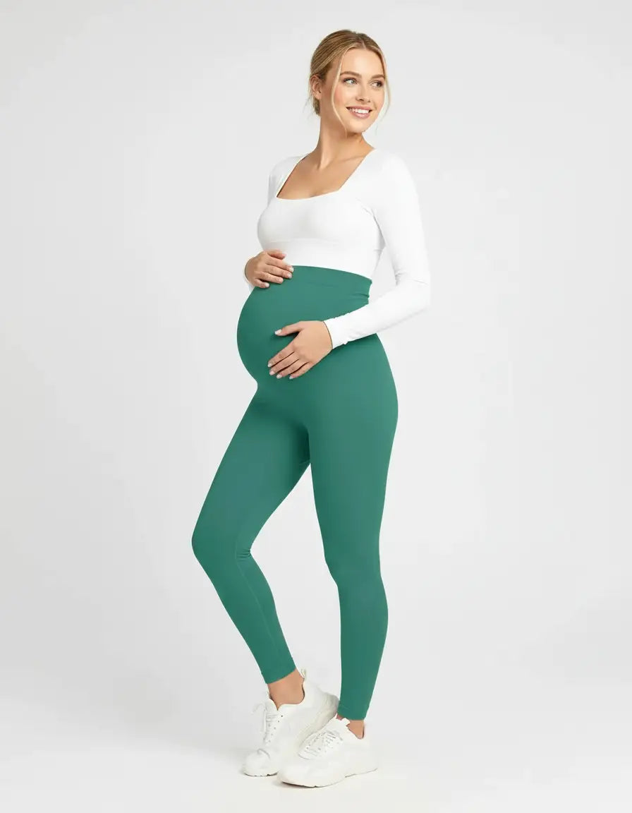 Smiling pregnant woman in soft-stretch full-length teal maternity leggings with a high, supportive waistband.