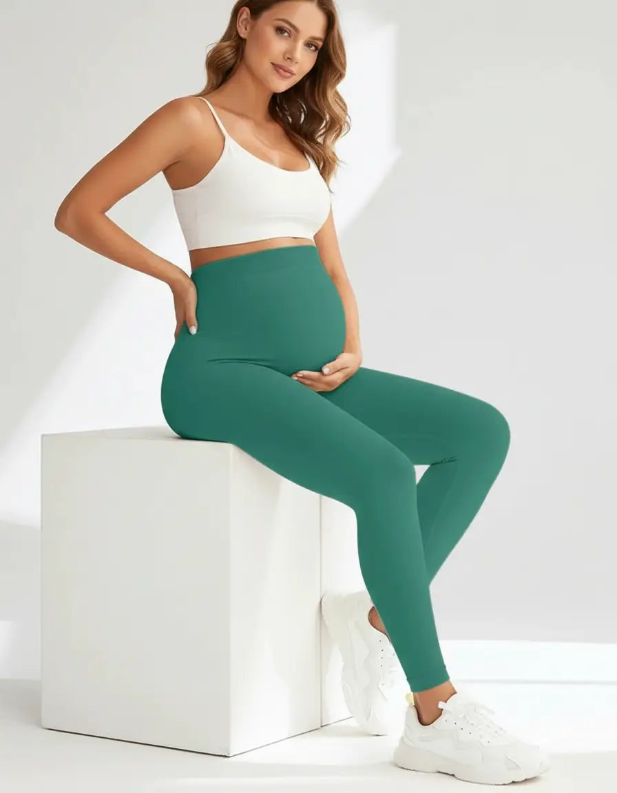 Pregnant woman in teal full-length soft-stretch maternity leggings and a white crop top.