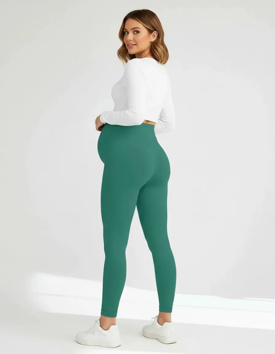 Smiling pregnant woman in full-length teal soft-stretch maternity leggings and a white top.