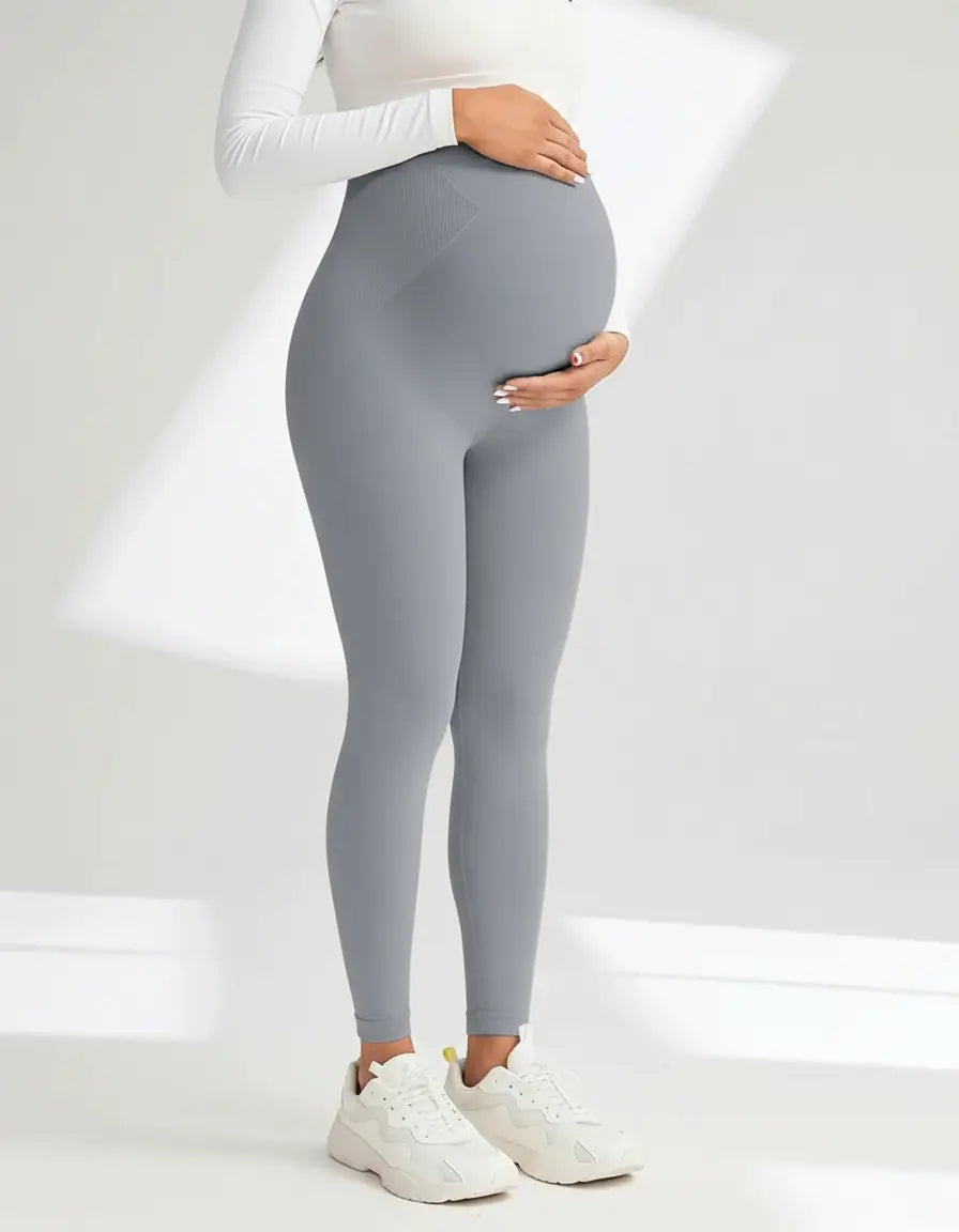 Pregnant woman wearing gray soft-stretch full-length maternity leggings with an over-the-bump design.
