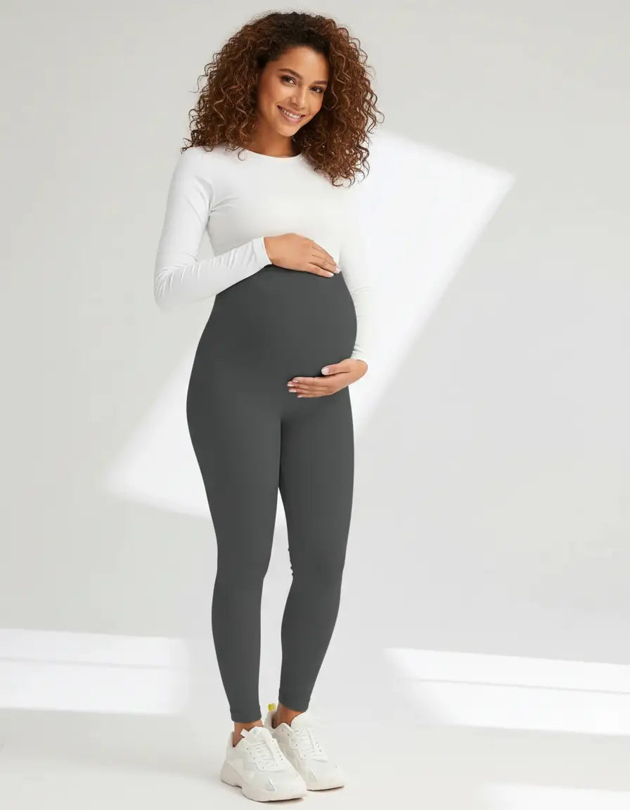 Smiling pregnant woman in dark gray soft-stretch full-length maternity leggings with an over-the-bump design.