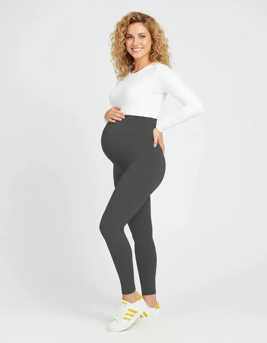 Smiling pregnant woman wearing dark gray soft-stretch full-length maternity leggings with a high, supportive waistband.