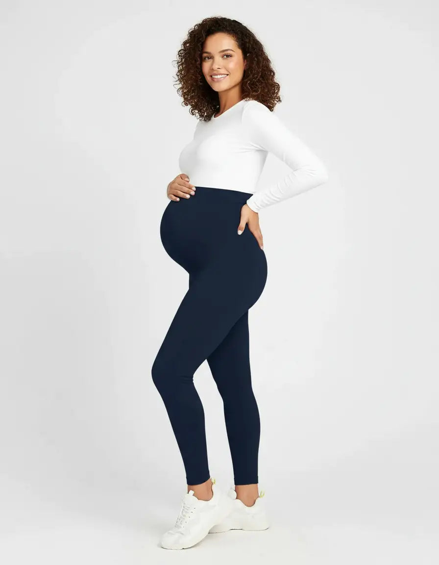 Smiling pregnant woman in navy full-length soft-stretch maternity leggings and a white long-sleeve top.