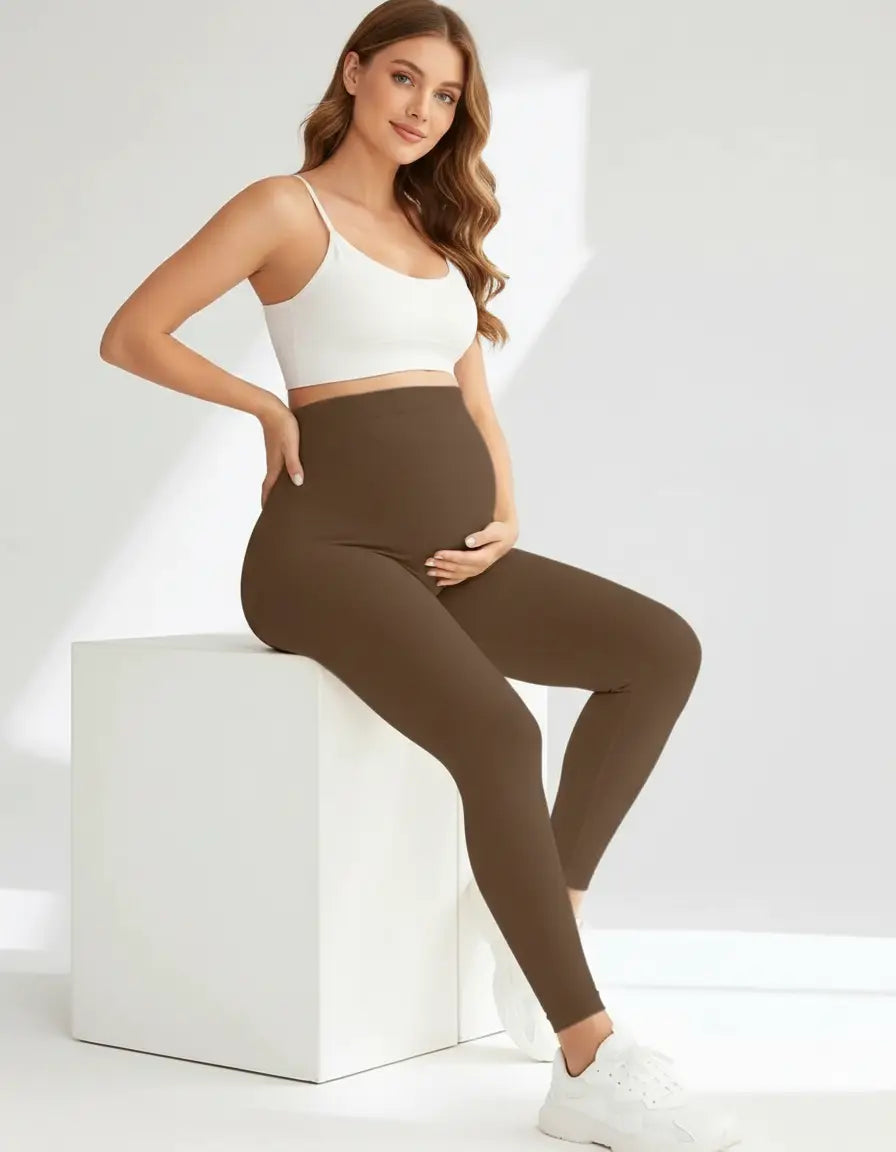 Pregnant woman in brown soft-stretch full-length maternity leggings and a white crop top.