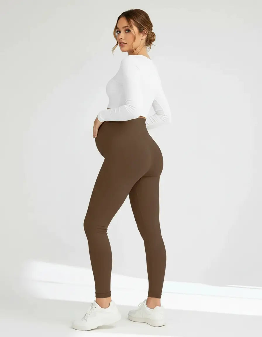 Pregnant woman wearing soft-stretch, full-length brown maternity leggings with a comfortable over-the-bump design.