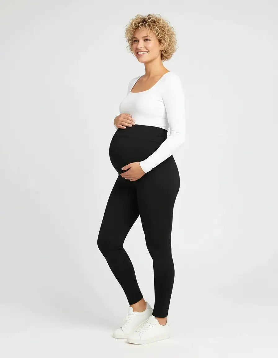 Smiling pregnant woman in black soft-stretch full-length maternity leggings with an over-the-bump panel.