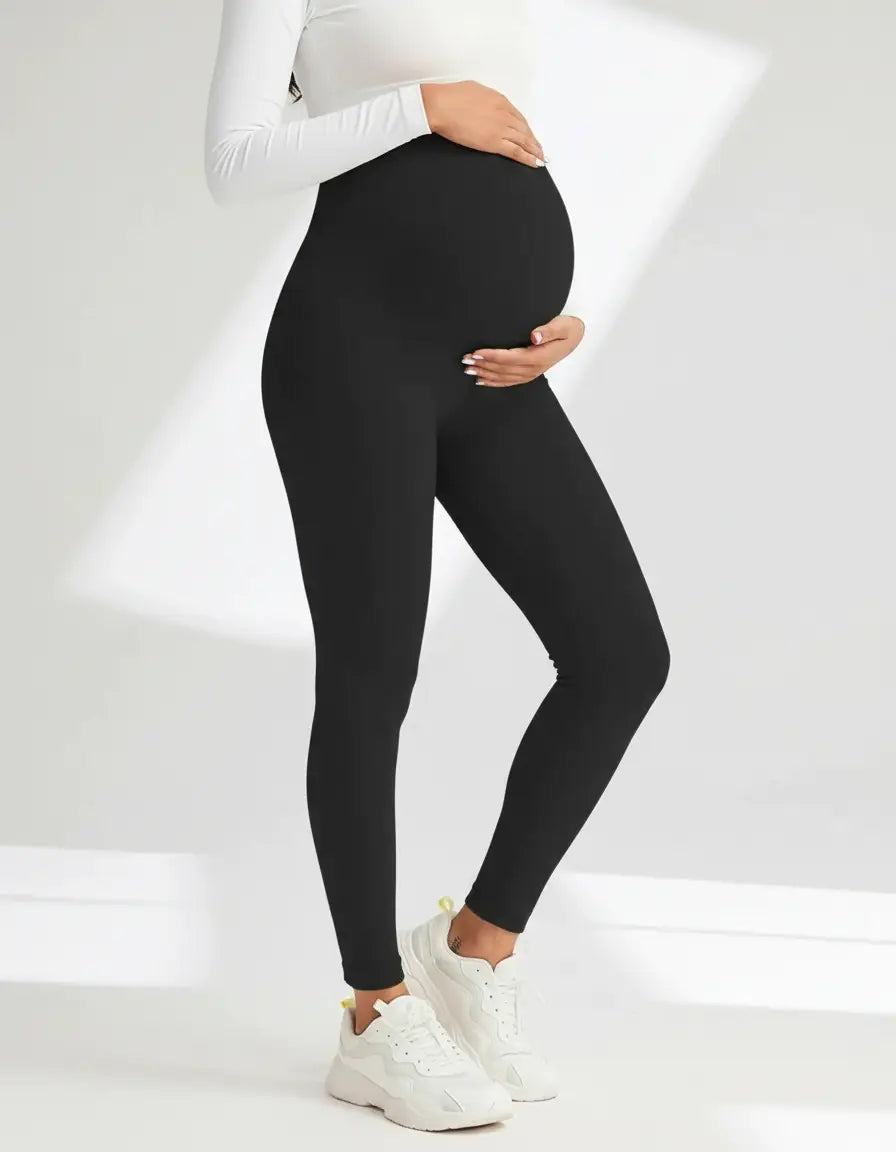 Pregnant woman wearing black soft-stretch full-length maternity leggings with an over-the-bump design.