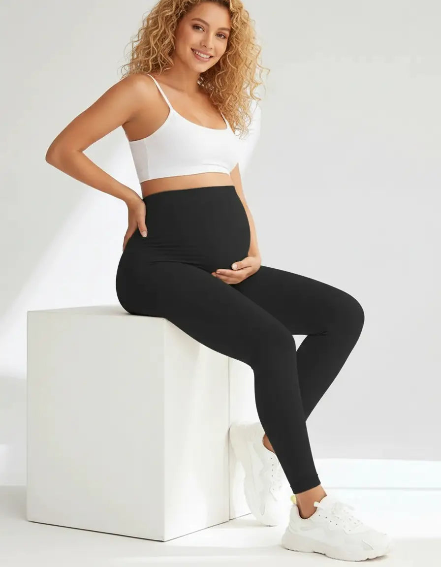 Smiling pregnant woman in black full-length soft-stretch maternity leggings and white crop top.