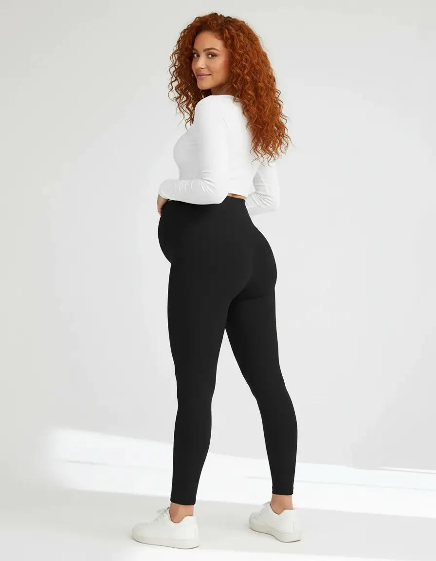 Pregnant woman in black soft-stretch full-length maternity leggings and a white long-sleeve top.