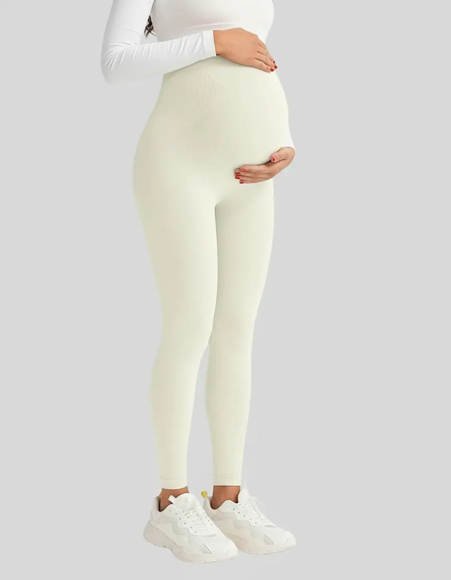 Pregnant woman wearing soft-stretch, full-length, cream-colored maternity leggings with a high, supportive waistband.