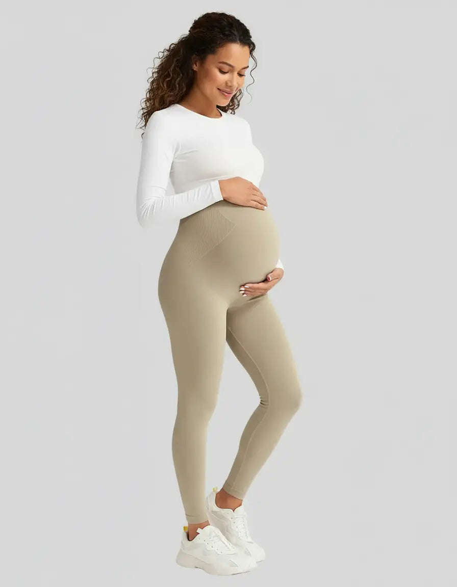 Smiling pregnant woman in beige soft-stretch full-length maternity leggings with a high, supportive waistband.