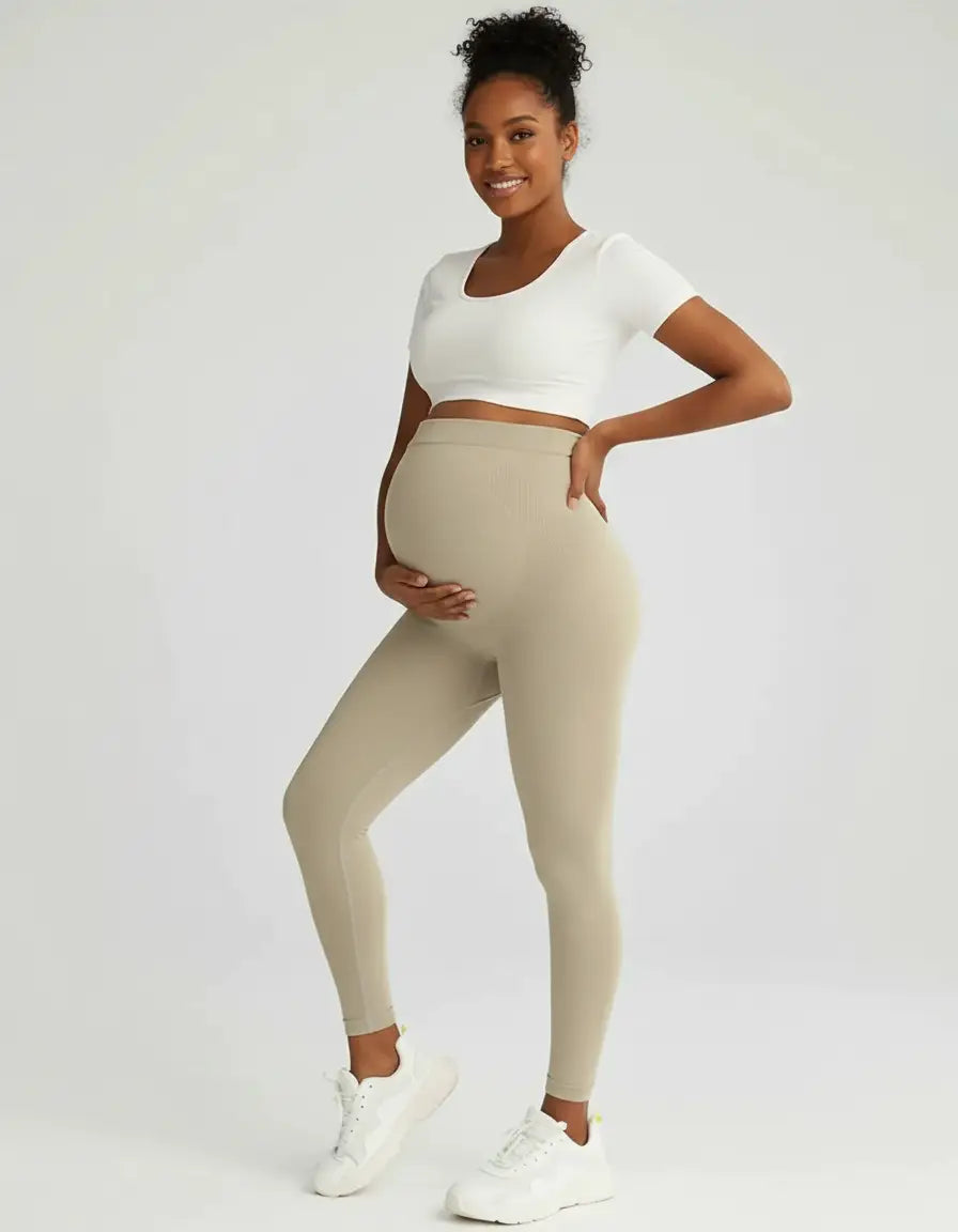 Smiling pregnant woman wearing full-length, soft-stretch beige maternity leggings with a ribbed high-waist.