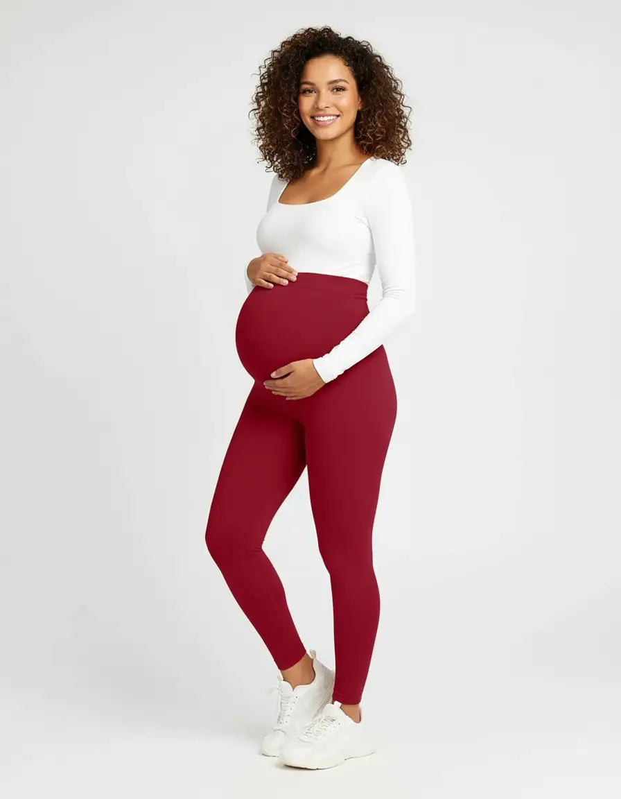 Smiling pregnant woman in full-length, soft-stretch, deep red maternity leggings with an over-the-bump waistband.