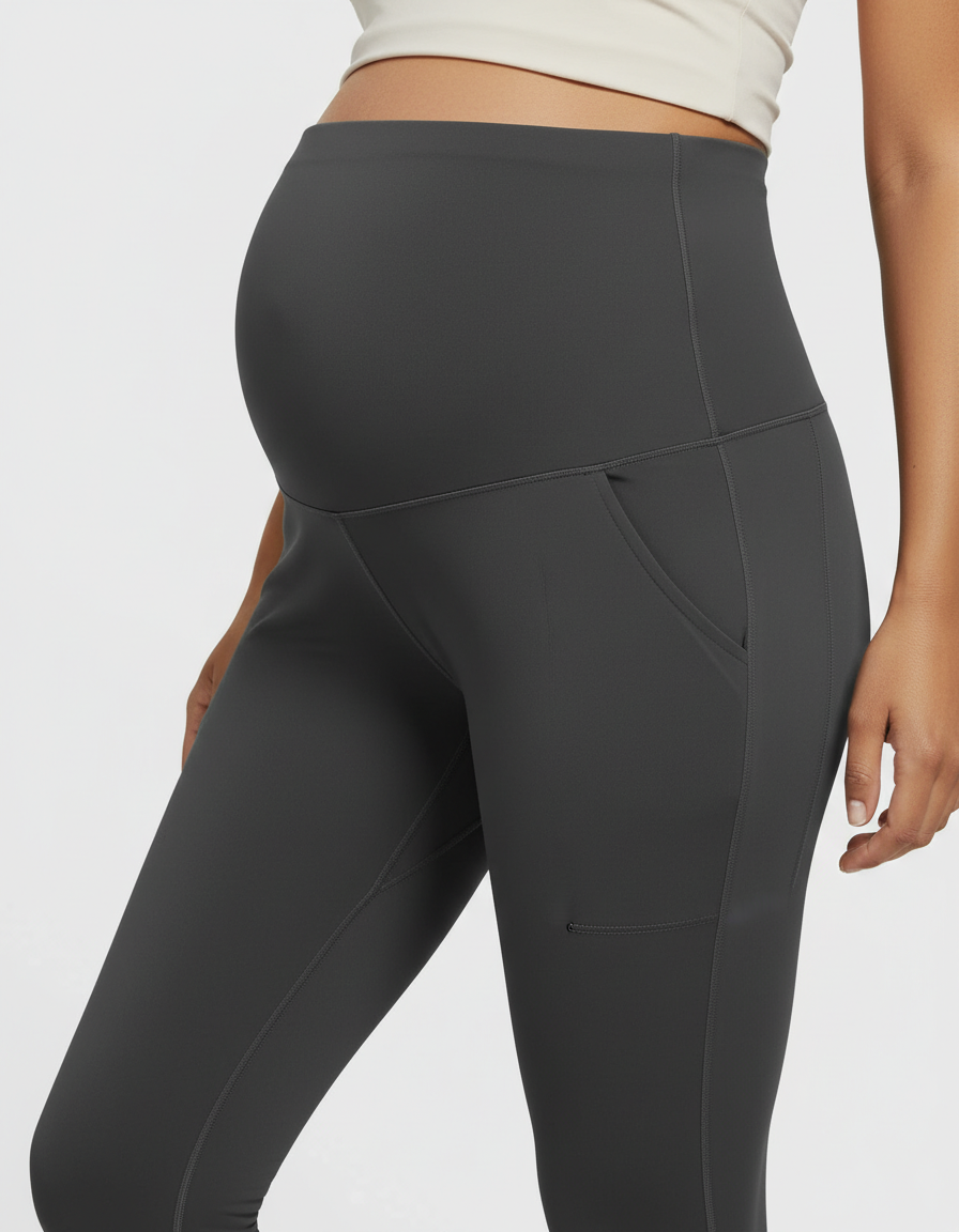 Dark gray high-rise maternity pants with belly support panel and side pockets, worn by a pregnant person.