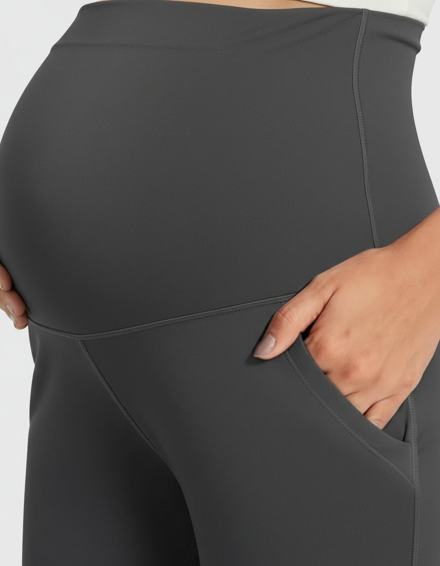 Dark gray high-rise wide-leg maternity pants with belly support panel and side pockets, worn by a pregnant woman.