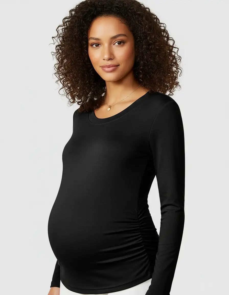 Smiling pregnant woman wearing a black long-sleeve thermal maternity top with side ruching.
