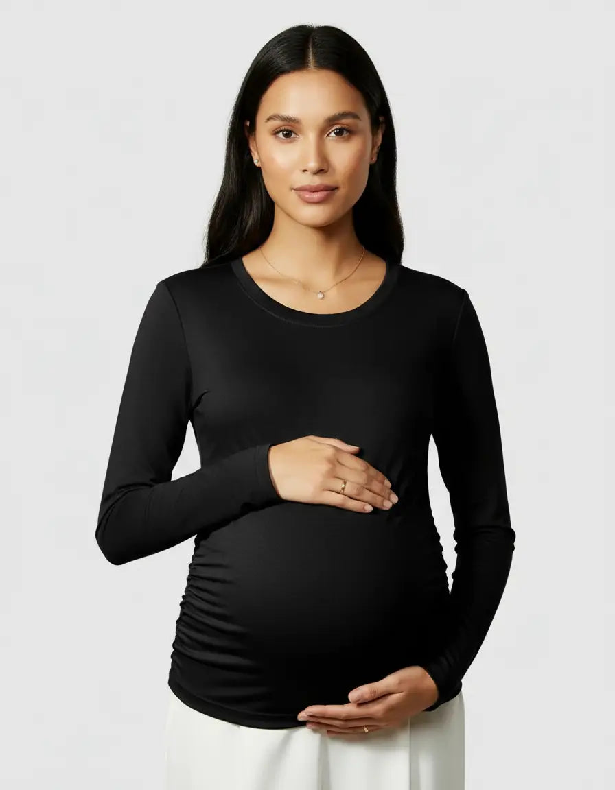 Pregnant woman in a black thermal long-sleeve maternity top with side ruching, hands on her baby bump.